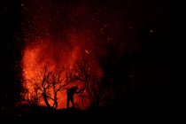 Силуэт фотографа против взрывающейся лавы и магмы, вытекающей из кратера. Извержение вулкана Кумбре-Вьеха на Канарских островах, Испания, 2021 г. — стоковое фото