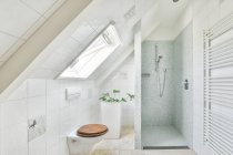 Diseño creativo de cuarto de baño con cuarto de baño y taza de inodoro debajo de la ventana en casa de luz - foto de stock