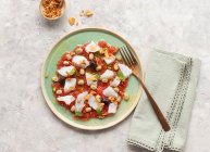 Літній помідор і салат з тріски в неглибокій тарілці з виделкою і мискою смаженої цибулі — стокове фото