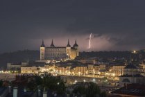 Cityscape with aged famous castle Alcazar of Toledo placed in Spain under cloudy sky in night time during thunderstorm — Stock Photo