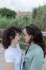 Вид сбоку на модную молодую женщину с гомосексуальной возлюбленной, смотрящую друг на друга на мосту — стоковое фото