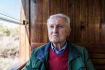Vista frontal de homem atraente e homem velho viajando em uma carruagem de madeira velha do trem que olha para fora da janela — Fotografia de Stock