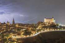 Paysage urbain avec vieux château célèbre Alcazar de Tolède placé en Espagne sous le ciel nuageux dans la nuit pendant l'orage — Photo de stock