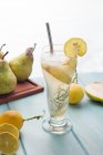 Dall'alto di cocktail di pera freddo in vetro con rosmarino e cubetti di ghiaccio messi sul tavolo con frutta fresca — Foto stock