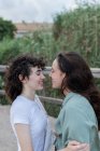Side view of trendy young woman with homosexual beloved looking at each other on bridge — Stock Photo