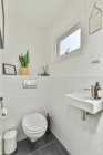 Pulito piccolo lavabo e servizi igienici in bagno luce pareti piastrellate bianche in appartamento moderno — Foto stock