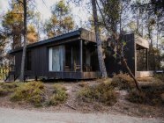 Casa de campo contemporânea com exterior de madeira e espaçoso terraço localizado na floresta à noite de verão — Fotografia de Stock