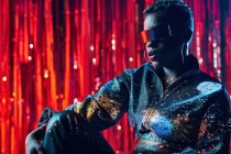 Trendy junge schwarze Frau in Cyberpunk-Brille mit Schatten im Gesicht im Lichtkegel in einem Nachtclub — Stockfoto