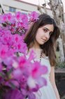 Gentle female teenager with brown hair in beads against blossoming violet flowers in city park — Stock Photo