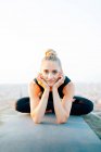 Ganzkörper-fitte Frau in Sportbekleidung praktiziert Ardha Padmasana und berührt Gesicht beim Outdoor-Yoga-Training bei Sonnenuntergang — Stockfoto