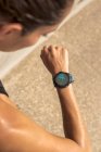 Сверху анонимная потная бегунья проверяет пульс на тренажере во время тренировки в солнечный день летом — стоковое фото