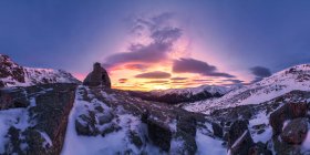 Picturesque landscape small aged stone house placed on snowy top of mountains under colorful cloudy sky at sunset — Stock Photo