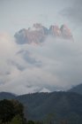 Pintoresco paisaje de montañas rocosas con altas pendientes empinadas cubiertas de espesa niebla y colinas cubiertas de bosques - foto de stock