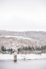 Landschaft von plätschernden Fluss fließt durch schneebedeckten Ufern mit blattlosen Bäumen, die auf Hügeln wachsen — Stockfoto