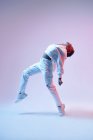 Енергетична етнічна жінка в бездротових навушниках і модний одяг стрибає з піднятою ногою і відкритим ротом під час танців хіп-хопу — стокове фото