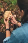 From above cropped unrecognizable female mycologist taking off dirt from Ramaria mushroom while in the woods — Stock Photo