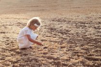 Вид сбоку маленькая блондинка одна в поле в солнечный день — стоковое фото