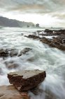 Espectacular paisaje con olas espumosas lavando formaciones rocosas rugosas de diversas formas en Silence Beach en Asturias España - foto de stock