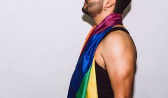 Врожай невідомий бородатий чоловік грає і махає різнокольоровий прапор символ гордості ЛГБТК — стокове фото