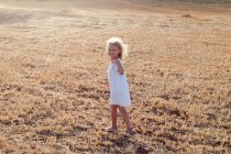 Petite fille blonde seule dans un champ par une journée ensoleillée — Photo de stock