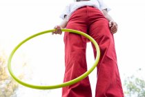 From below of crop unrecognizable female teen in red jeans holding hula hoop while having free time in park — Stock Photo