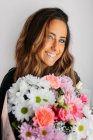 Retrato de linda menina adolescente em casa segurando flores bonitas e olhando para a câmera — Fotografia de Stock