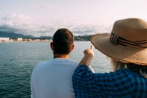 Back view of anonymous couple of tourists contemplating sea and mount under cloudy blue sky in Saint Jean de Luz — Stock Photo