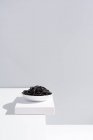 Минималистская студия с черными чернилами кальмара спагетти в полной керамической миске на белом столе — стоковое фото