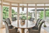 Diseño creativo de comedor y cocina con sillones y mesa bajo lámparas colgando de la pared de la ventana en casa - foto de stock