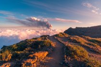 Salida del sol en un sendero de montaña de gran altitud en medio de nubes blancas suaves y gruesas y la erupción de un volcán en el fondo. Cumbre Vieja erupción volcánica en La Palma Islas Canarias, España, 2021 - foto de stock