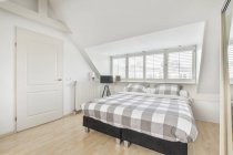 Bequemes weiches Bett mit weißer Bettdecke in der Nähe großer Fenster im modernen Schlafzimmer in der Wohnung — Stockfoto