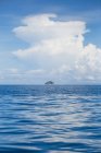 Paisaje de mar ondulado azul claro con isla rocosa en el horizonte bajo las nubes en el día soleado en Malasia - foto de stock