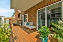 Couch und Tisch auf der Veranda des Wohnhauses mit Topfpflanzen in der Nähe von Glastüren — Stockfoto