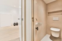 Design criativo do banheiro com banheiro montado na parede contra lavatório e vasos decorativos em parquet na sala de luz em casa — Fotografia de Stock