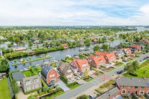 Vista drone de fachadas de edifícios residenciais entre rio e gramados com árvores sob céu nublado na província de Utrecht Países Baixos — Fotografia de Stock
