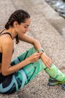 Женщина бегунья проверяет пульс на современном носимом фитнес-браслете во время тренировки в городе — стоковое фото