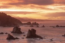 Spectacular scenery with foamy sea waves washing rough rocky formations of various shapes in Silence Beach in Asturias, Spain during sunset — Stock Photo