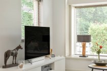 Великий зручний диван, розміщений навпроти телевізора у просторій вітальні зі стильним інтер'єром в сучасній квартирі — стокове фото