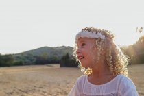 Vista lateral pequena menina loira sozinha em um campo em um dia ensolarado — Fotografia de Stock