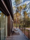 Сучасний котедж з дерев'яним екстер'єром і просторою терасою, розташованою в лісі в літній вечірній час — стокове фото