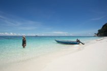 Seitenansicht einer ethnischen Touristin in Badeanzug und Strohhut, die während einer Reise in Malaysia im transparenten Meer steht — Stockfoto
