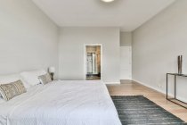 Modernes, geräumiges Schlafzimmer mit komfortablem Bett und Nachttisch in der Nähe von Teppich und Badezimmer — Stockfoto