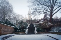 Alter verschneiter Park mit blattlosen Bäumen rund um die alte römisch-katholische Kirche Basilika des Heiligen Herzens von Paris auf dem Hügel Montmartre im Dunst — Stockfoto