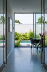 Leerer geräumiger Flur einer modernen Wohnvilla, der an sonnigen Tagen in einen Hinterhof mit Pool und Grünpflanzen führt — Stockfoto