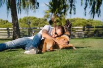 Junger bärtiger Mann mit Sonnenbrille liegt an Sommertag auf Wiese gegen reinrassigen Hund im Park — Stockfoto