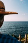 Vista posterior de la cosecha anónima viajera con sombrero contemplando un mar sin fin en Saint Jean de Luz Francia - foto de stock