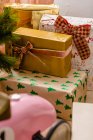 Sammlung von Weihnachtsgeschenken, eingewickelt in Papier und Bänder, die in der Nähe von Tannenzweigen platziert wurden — Stockfoto