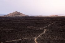 De cima rota áspera entre lava escura contra Caldera Blanca e Vulcões Caldereta no Parque Natural de Lanzarote Ilhas Canárias Espanha — Fotografia de Stock