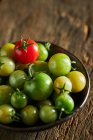 De dessus de tomates cerises vertes et rouges entières dans un bol recueilli à la ferme pendant la saison des récoltes — Photo de stock