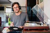 Focused man in eyeglasses listening to music in headphones from player in spacious apartment — Stock Photo